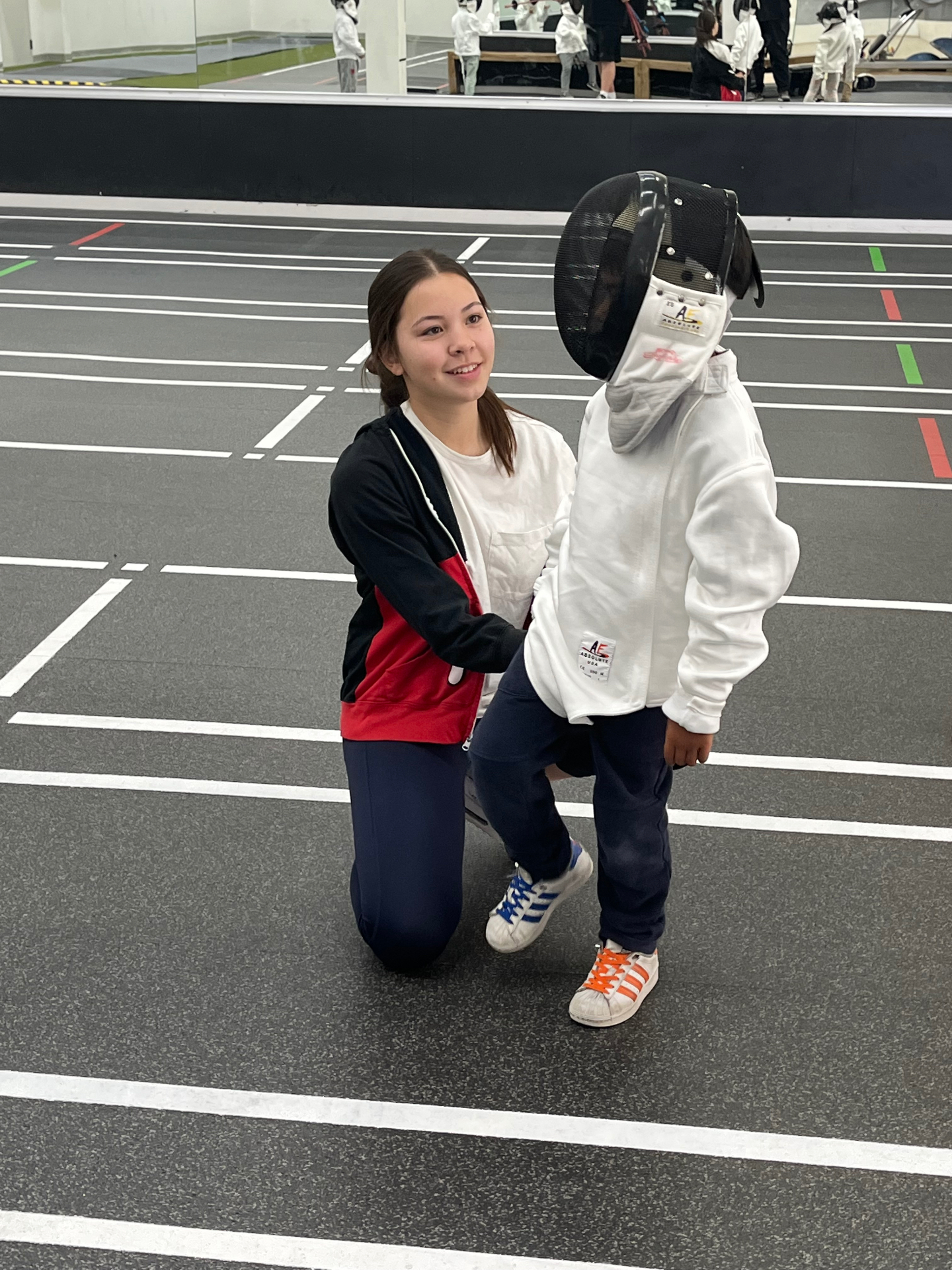 BAFC coach with a young Lil' Pirates fencer on the strip