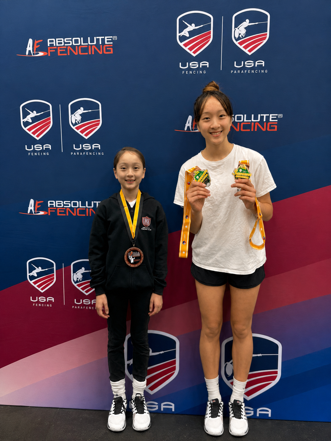 BAFC young fencers with tournament medals in front of USA Fencing backdrop